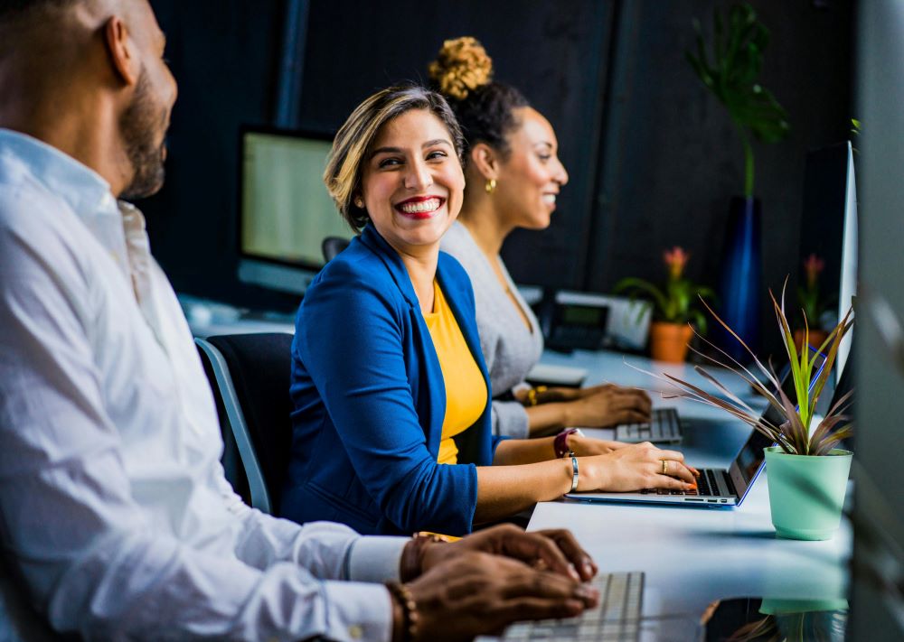 Smiling woman working in an office surrounded by colleagues 