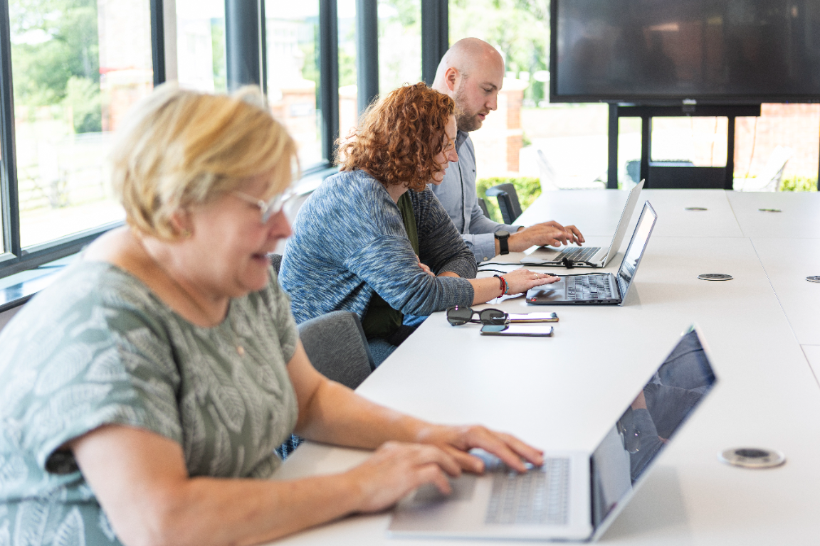 Three People sitting at desks looking at laptops, having digital skills training