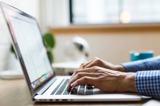 Man typing on a laptop keyboard.