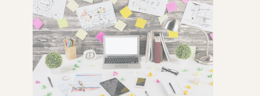 very busy and cluttered desk, with laptop and post it notes,
