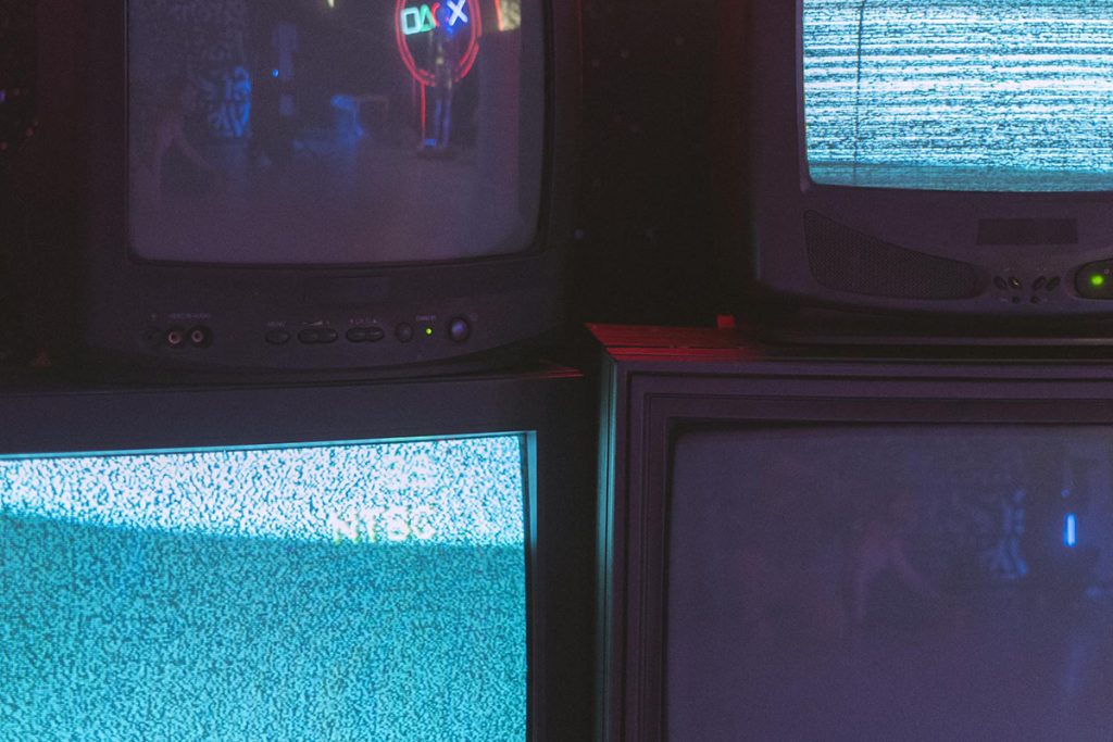 Some old television sets stacked on top of each other with static on some of the screens