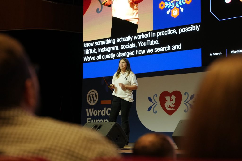 Photo of Hostinger's Emma Young presenting on stage at WordCamp Europe 2026